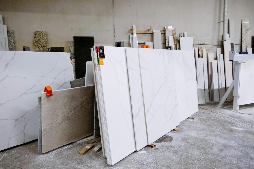 Wide view of granite and marble slabs neatly arranged in a factory setting, showcasing variety and texture.