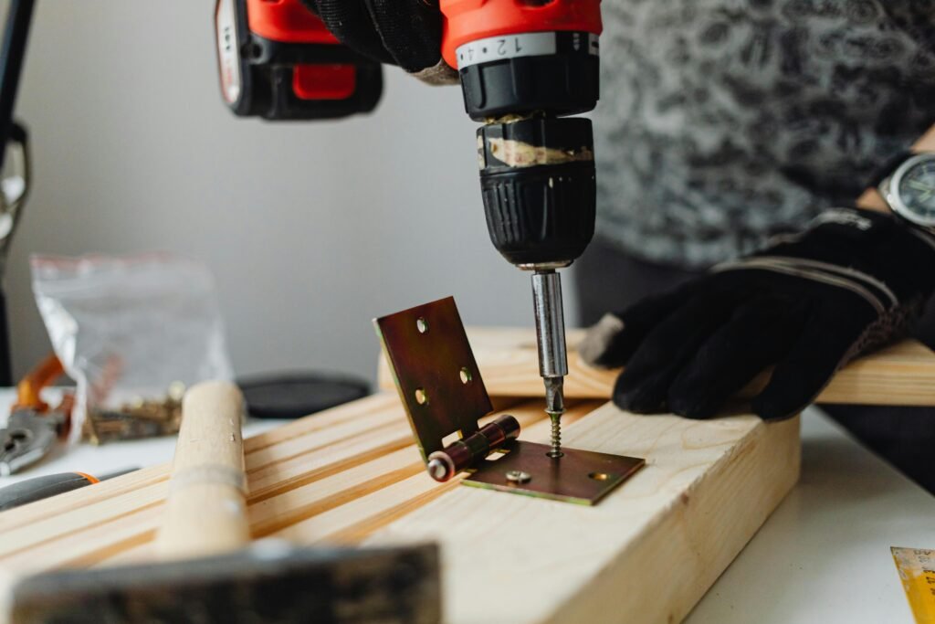 Close-up of a skilled carpenter using a power drill on wood in a workshop.